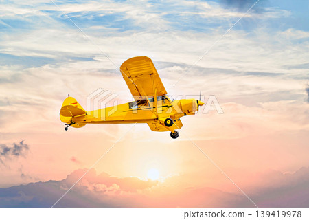 Single engine ultralight airplane flying under an orange sky at sunset Single engine ultralight airplane flying under an orange sky at sunset 139419978