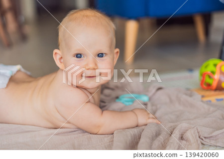 Baby lying on play mat learning to crawl and get on all fours. Infant practicing motor skills and development at home. Early childhood growth, milestones and active learning concept 139420060