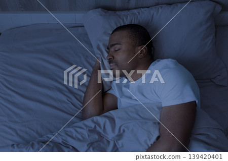Peaceful African american man sleeping at night in bed Peaceful African american man sleeping at night in bed 139420401