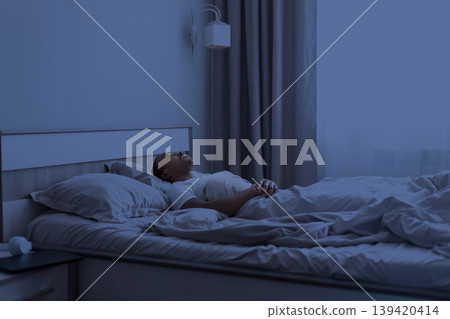 Sleepless African American man lying flat in bed at night, gazing up Sleepless African American man lying flat in bed at night, gazing up 139420414