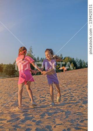 Children are spinning and having fun dancing on the beach by the sea at sunset. Children are spinning and having fun dancing on the beach by the sea at sunset. 139420531