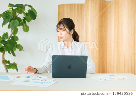 A young Japanese female business professional giving a presentation using a laptop and documents in the office. 139420586