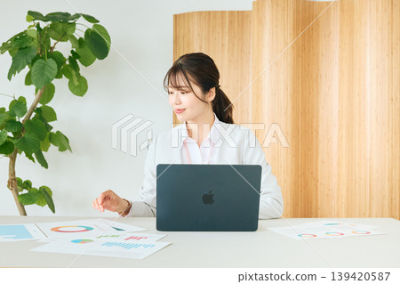 畫面顯示,一位年輕的女商務人士和一位身穿白色西裝的公司員工正在辦公室使用筆記型電腦和文件分析數據。 畫面顯示,一位年輕的女商務人士和一位身穿白色西裝的公司員工正在辦公室使用筆記型電腦和文件分析數據。 139420587