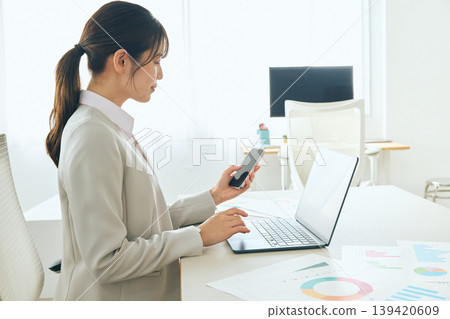 Young female business professionals and office workers who use smartphones and laptops for work at their desks. 139420609