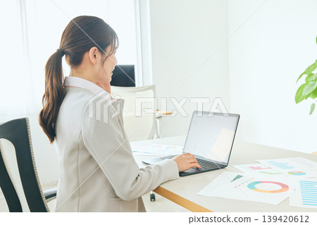 A young businesswoman and a company employee in a suit are seen in the office, with the employee checking documents on a laptop. A young businesswoman and a company employee in a suit are seen in the office, with the employee checking documents on a laptop. 139420612
