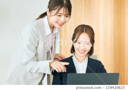 辦公室裡有兩位女企業家,一位資深員工一邊看著筆記型電腦螢幕,一邊指導和培訓一位初級同事。 辦公室裡有兩位女企業家,一位資深員工一邊看著筆記型電腦螢幕,一邊指導和培訓一位初級同事。 139420625