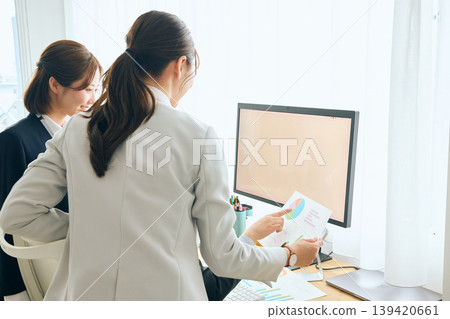 Two female business professionals are having a meeting in the office, looking at graphs and data: teamwork and work reporting. 139420661