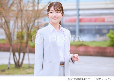 一位身穿西裝的年輕女子在春日戶外微笑——這個形象可能是商務人士、新員工或求職者。 一位身穿西裝的年輕女子在春日戶外微笑——這個形象可能是商務人士、新員工或求職者。 139420769
