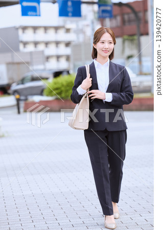 身著職業套裝的年輕女性走在城市街道上的肖像,以及正在尋找工作的女大學生的肖像。 身著職業套裝的年輕女性走在城市街道上的肖像,以及正在尋找工作的女大學生的肖像。 139420777