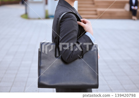 身穿西裝的女士手提黑色商務包-這是求職或通勤的畫面。 身穿西裝的女士手提黑色商務包-這是求職或通勤的畫面。 139420798
