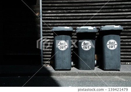 In contrast to the tranquility of the city: black dust carts lined up in the alley and sharp lights. In contrast to the tranquility of the city: black dust carts lined up in the alley and sharp lights. 139421479