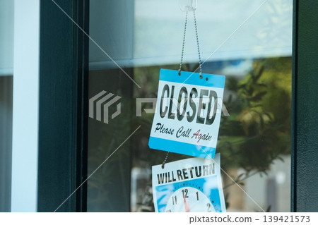 Urban store scene: "CLOSED" and "WILL RETURN" signs visible through the glass. Urban store scene: "CLOSED" and "WILL RETURN" signs visible through the glass. 139421573