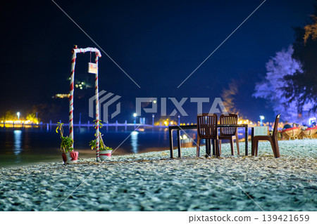 Cozy night seating area on Koh Rong beach with table chairs and red white striped arch Cozy night seating area on Koh Rong beach with table chairs and red white striped arch 139421659