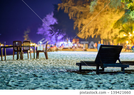Two wooden beach loungers on white sand under lush trees at night on Koh Rong Cambodia Two wooden beach loungers on white sand under lush trees at night on Koh Rong Cambodia 139421660