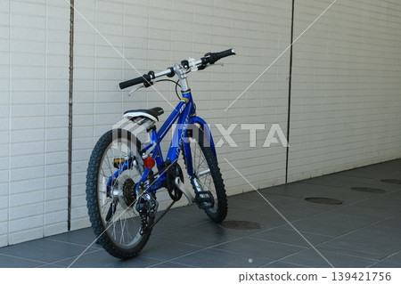 A blue children's mountain bike parked on a street corner: an active lifestyle 139421756