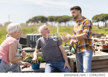 Mature couple and man argue with each other while standing near fence on small farm Mature couple and man argue with each other while standing near fence on small farm 139422691