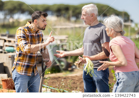 Elderly couple and young man arguing on farm field Elderly couple and young man arguing on farm field 139422743