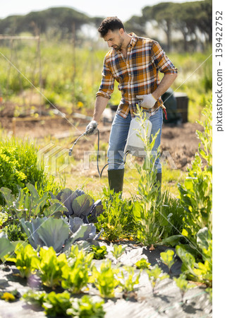 Young man spraying plants on farm field Young man spraying plants on farm field 139422752