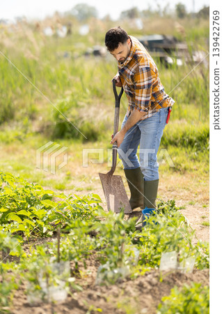 Young man with shovel working on farm field Young man with shovel working on farm field 139422769