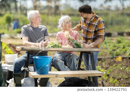 Happy family of farmers sits at table and discusses current affairs Happy family of farmers sits at table and discusses current affairs 139422791