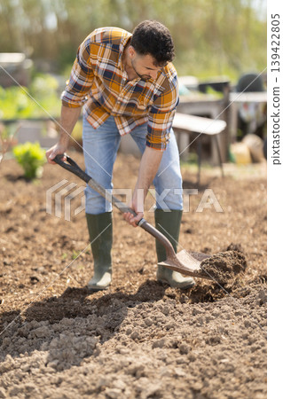 Young man with shovel working on farm field Young man with shovel working on farm field 139422805