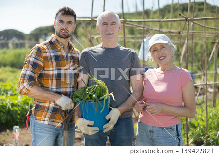 Portrait of happy family with an adult son and harvest of onions in their hands Portrait of happy family with an adult son and harvest of onions in their hands 139422821