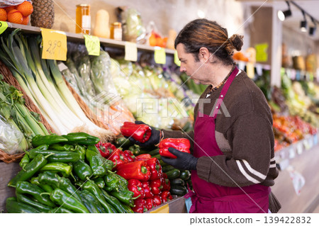 Man shop seller puts pepper goods on display case Man shop seller puts pepper goods on display case 139422832