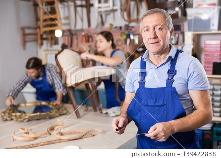 Confident successful craftsman restorer in uniform looking at camera in furniture repair woodwork shop Confident successful craftsman restorer in uniform looking at camera in furniture repair woodwork shop 139422838