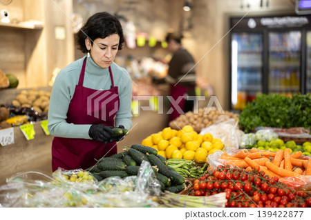 Adult woman seller puts cucumbers on display 139422877