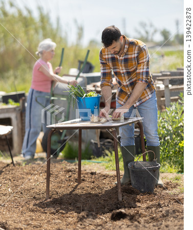 Man works in garden outdoors - preparing various tools for caring for plants 139422878