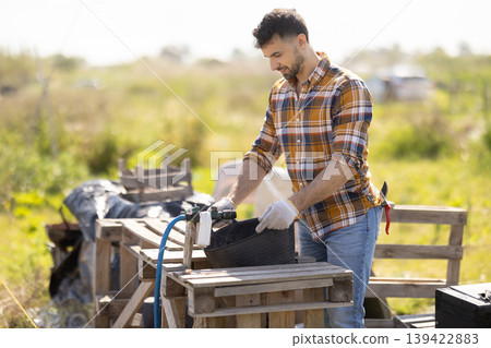 Young man filling bucket with water for field irrigation 139422883