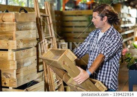Attentive man choosing wooden pallets in garden store Attentive man choosing wooden pallets in garden store 139422914