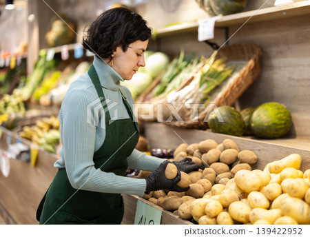 Woman shop seller puts potato goods on display case Woman shop seller puts potato goods on display case 139422952
