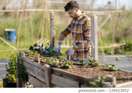 Man works in garden outdoors - preparing various tools for caring for plants 139423052