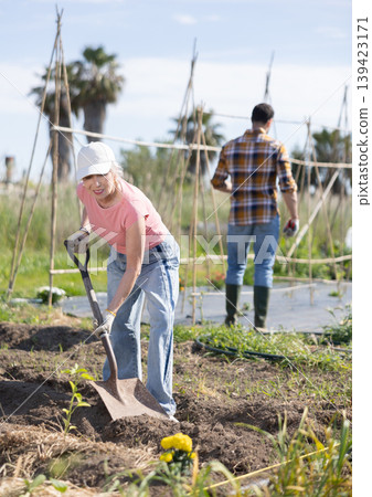 Elderly woman with shovel working on farm field Elderly woman with shovel working on farm field 139423171