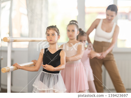 Girls in ballet class perform first position with correction of female mentor 139423697