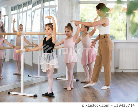 Little ballerinas learn to get into fourth position in ballet class. Choreographer helps them with this Little ballerinas learn to get into fourth position in ballet class. Choreographer helps them with this 139423714