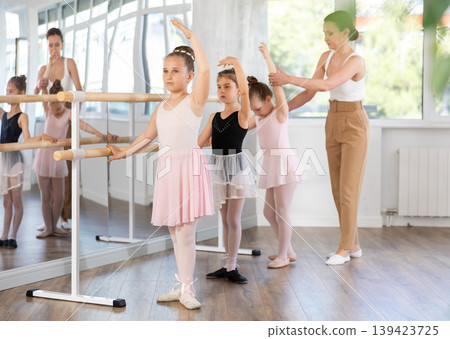 Girls in ballet class perform third position with correction of female mentor Girls in ballet class perform third position with correction of female mentor 139423725