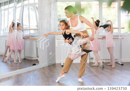 Woman teacher corrects movement of girl dancer Woman teacher corrects movement of girl dancer 139423730