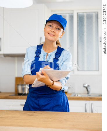 Woman house cleaner making notes in kitchen 139423748