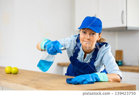 Skilled woman house cleaner sanitizing kitchen countertop Skilled woman house cleaner sanitizing kitchen countertop 139423750