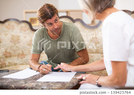 Mature woman and man doing paperwork together Mature woman and man doing paperwork together 139423764