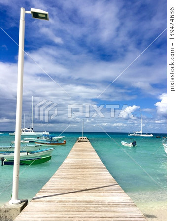 Bright tropical wooden pier with turquoise sea and dramatic blue cloudy sky, vibrant travel destination background Bright tropical wooden pier with turquoise sea and dramatic blue cloudy sky, vibrant travel destination background 139424636