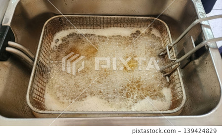 Deep Frying Food in Hot Boiling Oil Inside a Professional Wire Mesh Basket 139424829