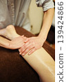 The hands of a therapist giving an oil massage to a woman's calf at a beauty salon. 139424866