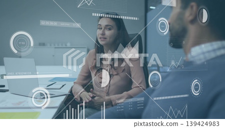 Businesswoman wearing blouse discussing data in meeting room, with laptop and data visualizations 139424983