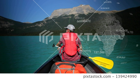 Paddling man wearing red life vest in canoe with backpack on turquoise lake, with globe overlay Paddling man wearing red life vest in canoe with backpack on turquoise lake, with globe overlay 139424990