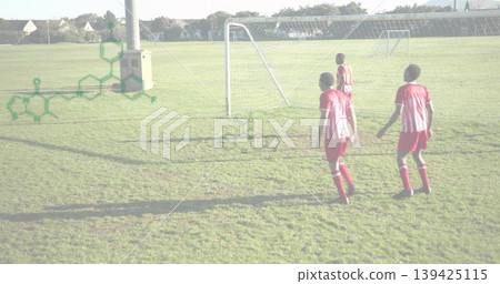 Walking four soccer players crossing grass at park toward metal goal near utility pole, copy space 139425115