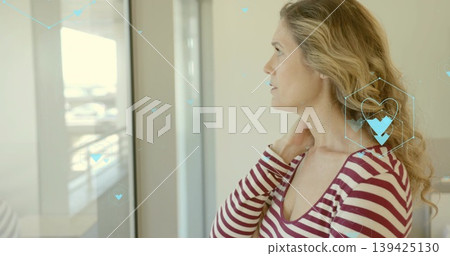 Gazing woman in striped top touching neck by glass window, with health hexagon graphics, copy space Gazing woman in striped top touching neck by glass window, with health hexagon graphics, copy space 139425130