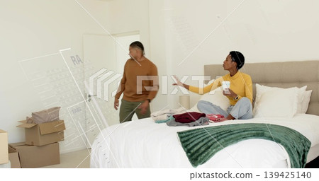 Couple arranging belongings in bright bedroom, with cardboard moving boxes and folded clothes Couple arranging belongings in bright bedroom, with cardboard moving boxes and folded clothes 139425140